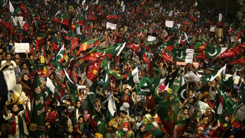 پی ٹی آئی کے جھنڈے اٹھائے احتجاجی مظاہرے میں شریک کارکنان۔